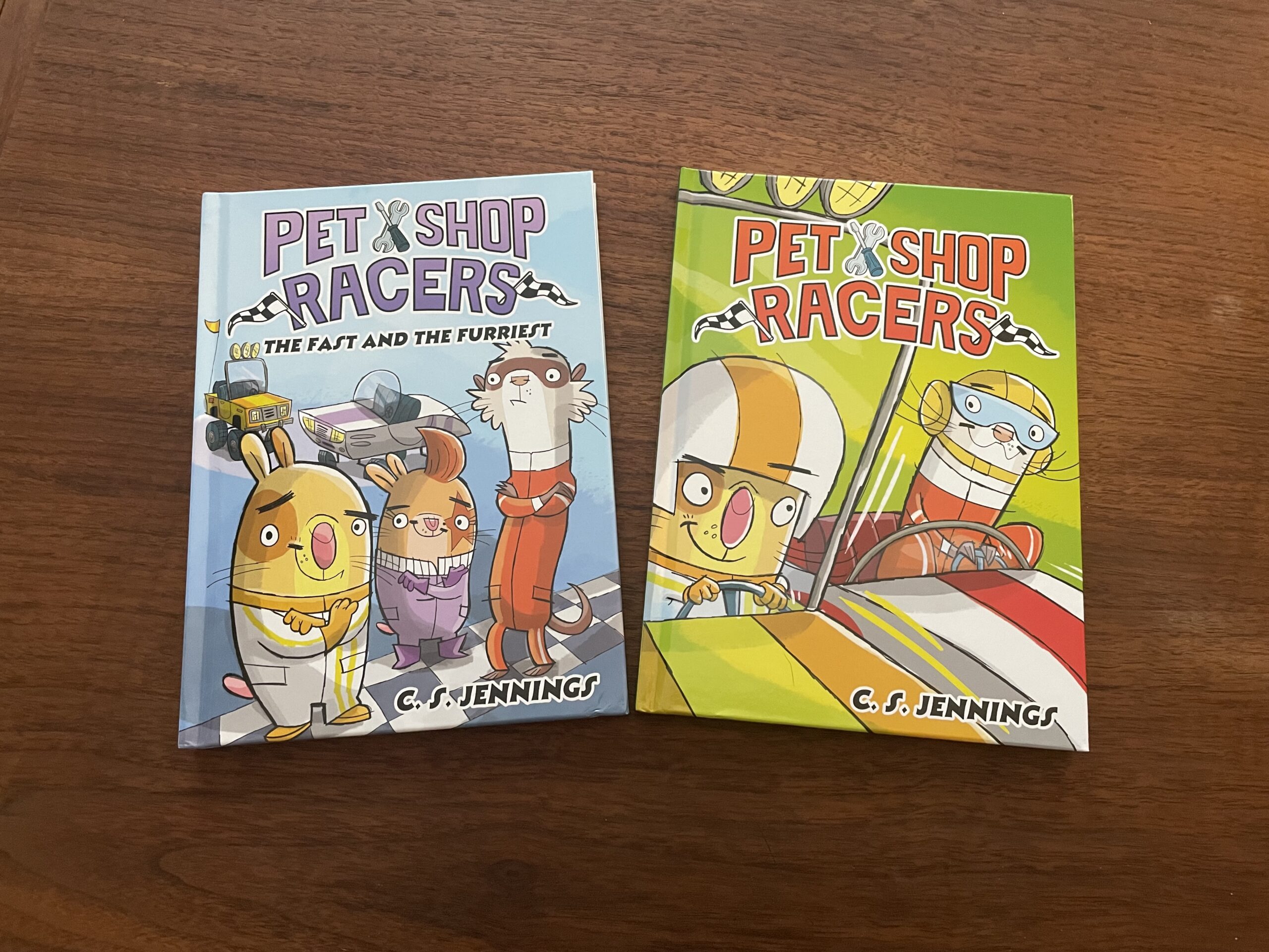 two books on a wooden surface - the children's titles are Pet Shop Racers books one and two