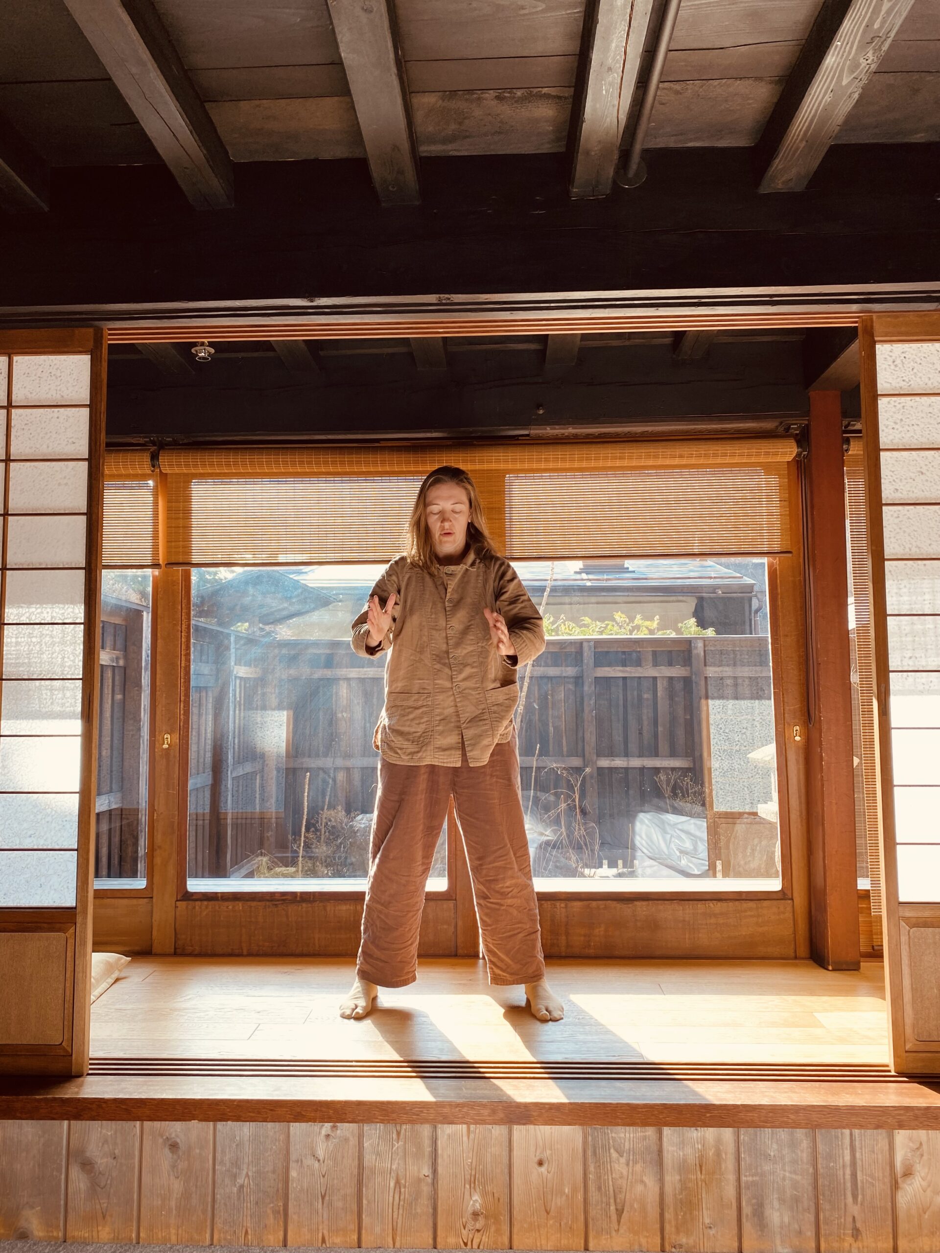 Amber wearing all brown clothing holding a qigong pose