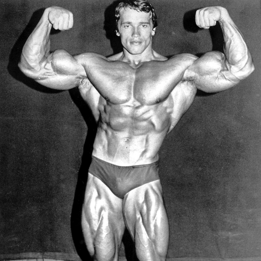 a black and white photo of Arnold Schwarzenegger in 1974, flexing his muscles