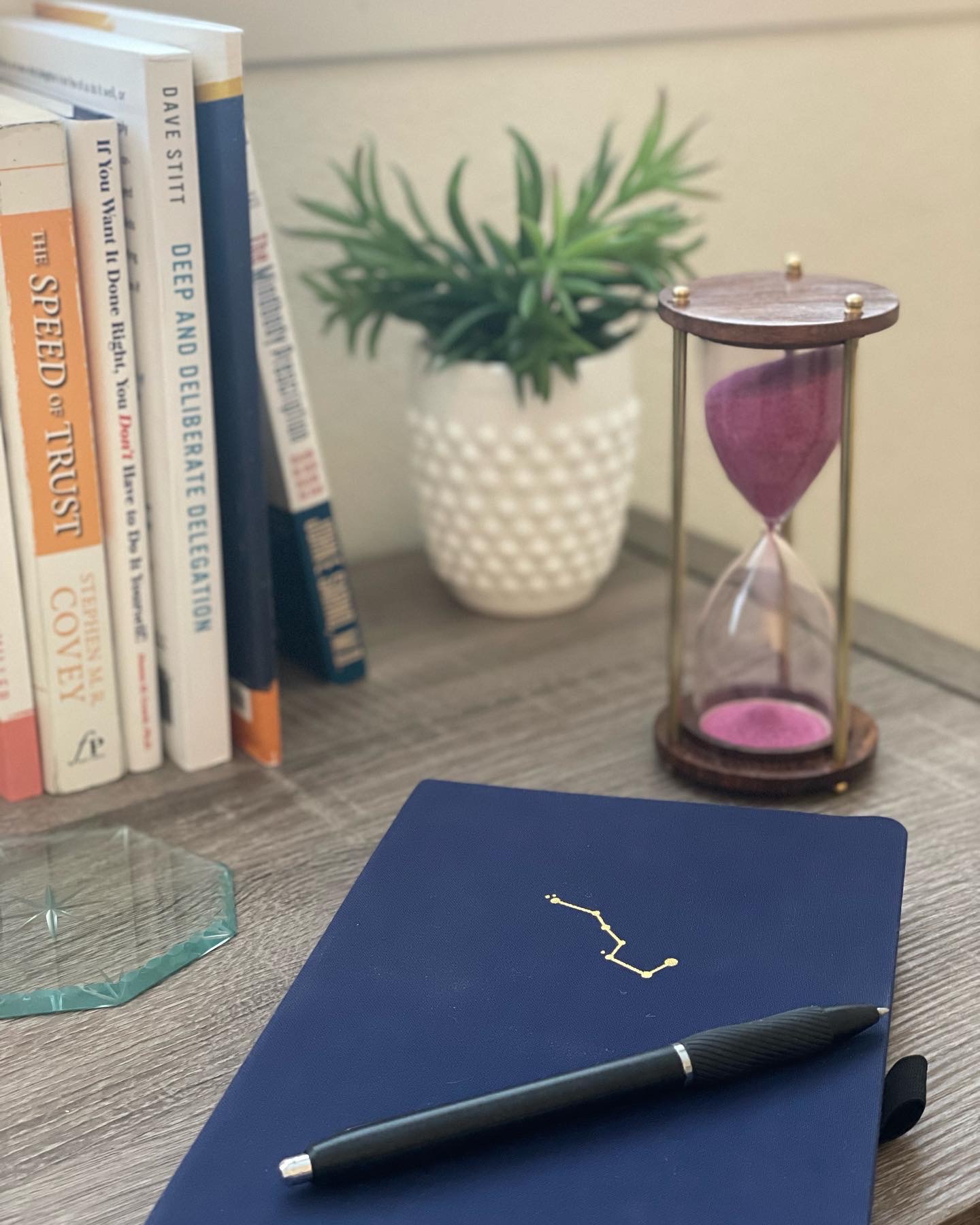 a blue journal next to a small hourglass with purple sand