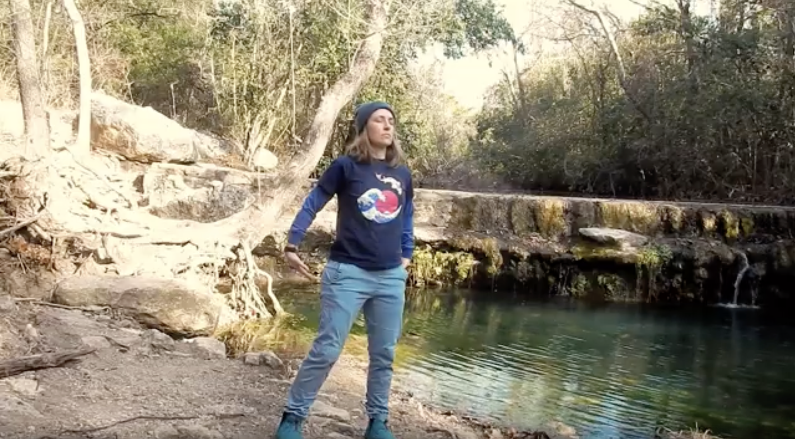 Amber holding the qigong Bear posture next to a waterfall