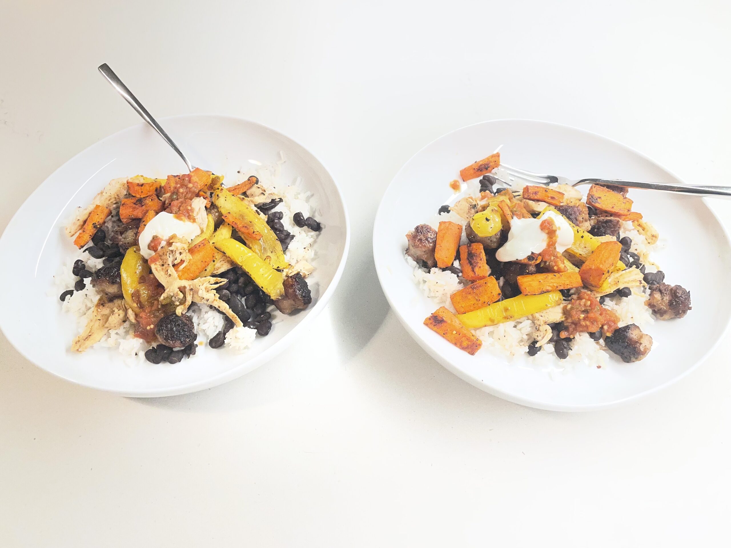 two plates of food - rice, black beans, veggies, and sausage