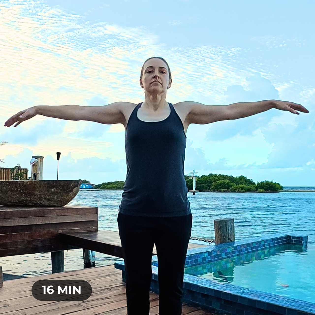 Amber, a woman wearing a gray tank top and black sweat pants standing with arms out to either side in a T shape
